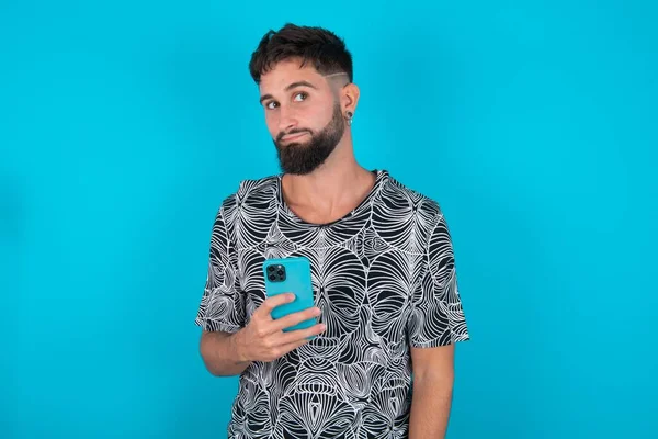 Young Hispanic Bearded Man Standing Blue Background Holds Mobile Phone — Stock Photo, Image