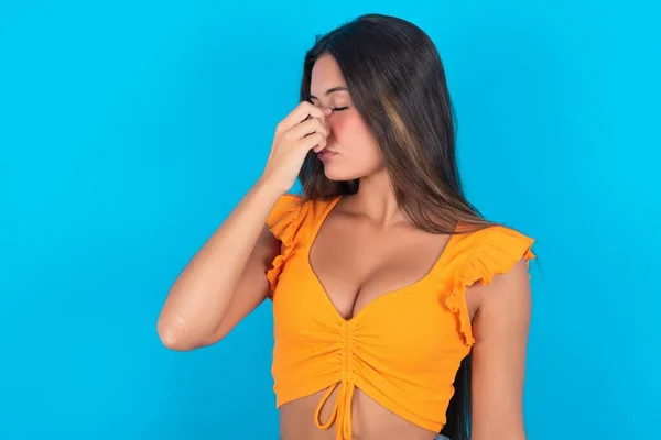 非常烦躁 漂亮的黑发女人 身穿橙色的背心 头戴蓝色的衬裙 紧闭双眼 触摸鼻梁 有压力的关系 或工作上有问题 — 图库照片