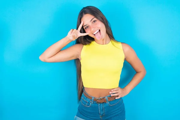 Mooie Brunette Vrouw Dragen Gele Tank Top Blauwe Achtergrond Maken — Stockfoto