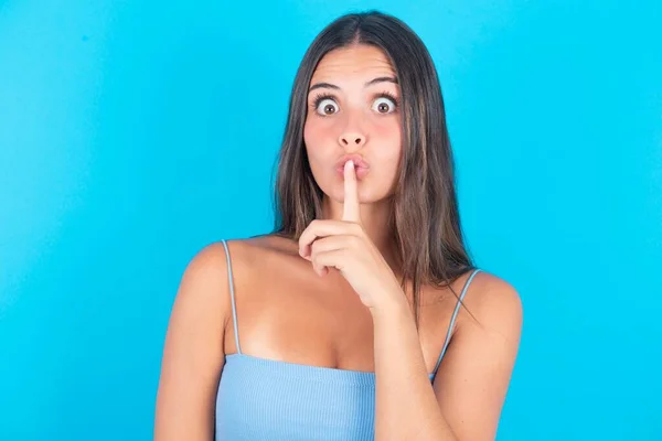 Surprised Brunette Woman Wearing Blue Tank Top Makes Silence Gesture — Stock Photo, Image