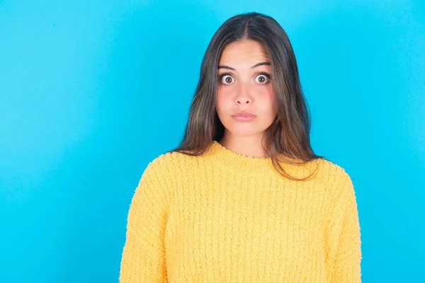 Jovem Morena Atordoada Usando Suéter Amarelo Sobre Fundo Azul Olha — Fotografia de Stock