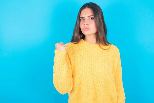 Joven Morena Mujer Vistiendo Suéter Amarillo Sobre Fondo Azul Venganza —  Fotos de Stock