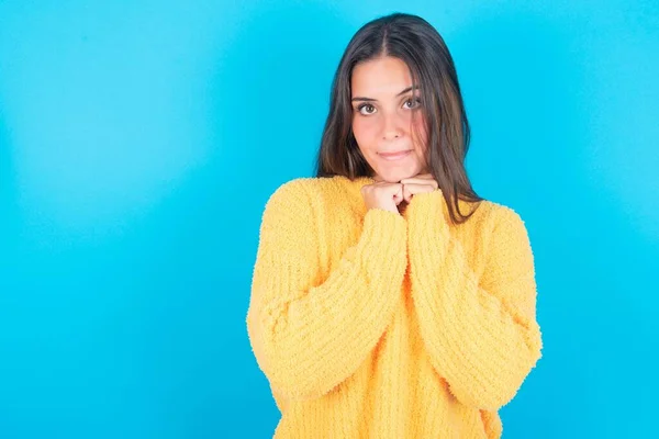 Curiosa Morena Con Suéter Amarillo Mantiene Las Manos Bajo Barbilla —  Fotos de Stock
