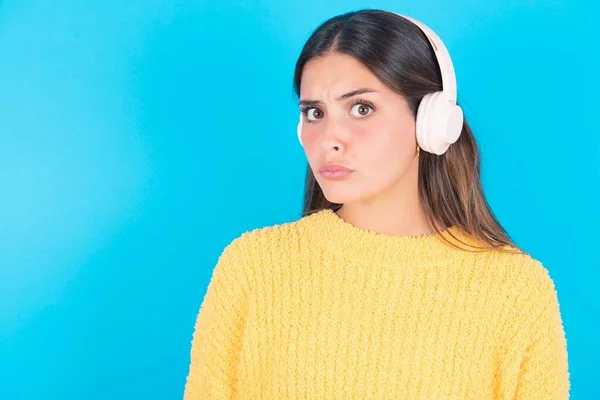 Mujer Morena Seria Auriculares Estéreo Con Suéter Amarillo Desconcertado Cámara —  Fotos de Stock