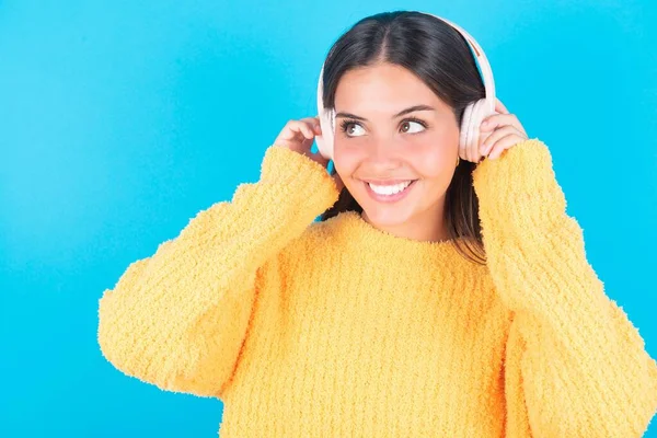Joven Morena Alegre Vistiendo Suéter Amarillo Sobre Fondo Azul Escucha —  Fotos de Stock