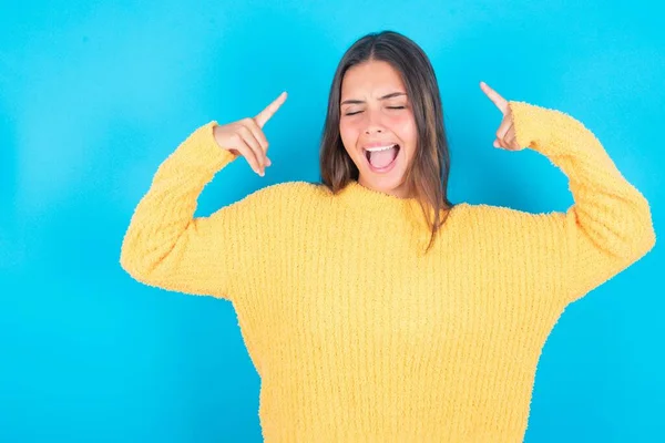 Mavi Arka Planda Sarı Süveter Giyen Çılgın Esmer Kadının Fotoğrafı — Stok fotoğraf