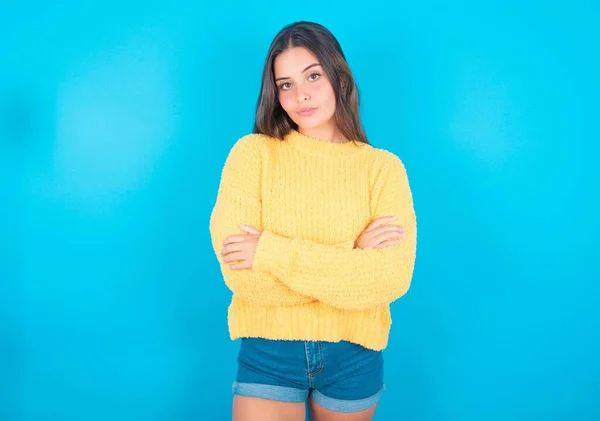 Pewna Siebie Młoda Brunetka Kobieta Żółtym Swetrze Niebieskim Tle Ramionami — Zdjęcie stockowe