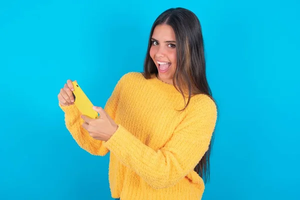 Nice Young Brunette Woman Wearing Yellow Sweater Blue Background Using — Stock Photo, Image