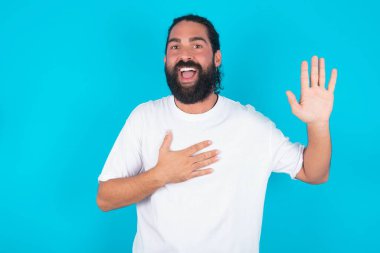 Yemin ederim, pişman olmayacağına söz ver. Mavi arka planda beyaz tişört giyen, beyaz sakallı, samimi beyaz bir adamın portresi. Bir kolunu kaldırıyor ve kalbe dokunuyor. Yemin ediyor, doğruyu söylüyor..