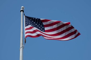 Mavi gökyüzü zafer bayramına karşı rüzgarda savrulan Amerikan bayrağı