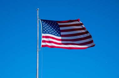 Mavi arka planda rüzgarda Amerikan bayrağı