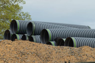 Büyük siyah plastik kanalizasyon boruları dışarıda yatıyor.