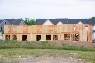 A residential house construction project showing plywood roof and dormer sheathing and oriented strand board or chipboard sheathing on the exterior walls new