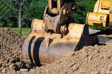 Closeup bucket of backhoe digging the soil at construction site crawler excavator digging on demolition site earthmoving equipment shovel yellow outdoor