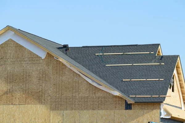 edge of roof shingles on top of the house, dark asphalt tiles on the roof grey rooftop