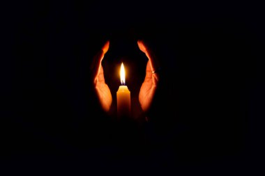 Mum ışığı alevini ellerimle koruyorum.