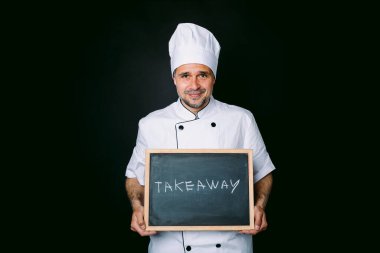 Beyaz ceketli ve şapkalı aşçı elinde siyah arka planda 