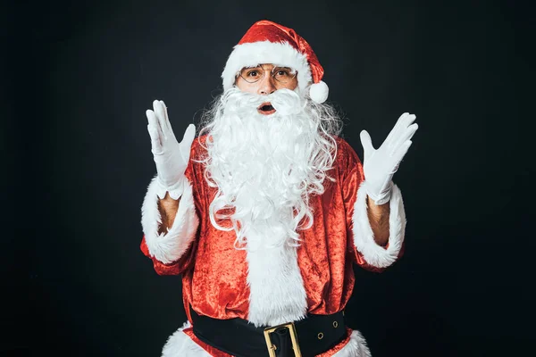 Człowiek Ubrany Jak Święty Mikołaj Zaskoczony Podniesionymi Rękami Czarnym Tle — Zdjęcie stockowe