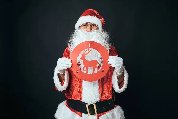身穿圣诞老人服装 手持禁止使用驯鹿交通标志的人 背景是黑色的 圣诞观念 圣诞老人 庆祝活动 — 图库照片