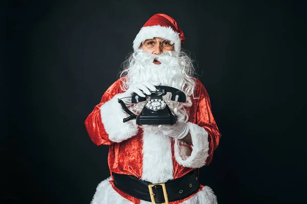 穿成圣诞老人的男人拿着60年代的复古电话 背景是黑色的 圣诞观念 圣诞老人 庆祝活动 — 图库照片