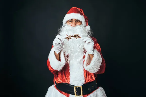穿得像圣诞老人的男人拿着一颗星星 背景是黑色的 圣诞老人 庆典的概念 — 图库照片