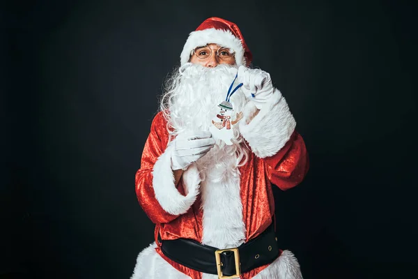 穿得像圣诞老人的人拿着雪人的雕像 背景是黑色的 圣诞老人 庆典的概念 — 图库照片