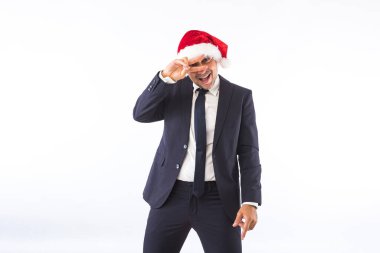 Takım elbiseli, kravatlı, Noel Baba şapkalı beyaz arka planda eğlenen bir iş adamı. Noel kutlaması kavramı.