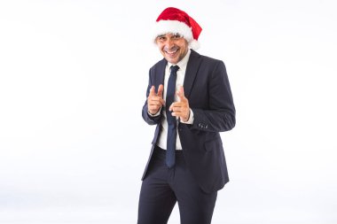 Takım elbiseli, kravatlı, Noel Baba şapkalı beyaz arka planda eğlenen bir iş adamı. Noel kutlaması kavramı.