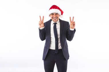 Takım elbiseli, kravatlı, Noel Baba şapkalı beyaz arka planda eğlenen bir iş adamı. Noel kutlaması kavramı.