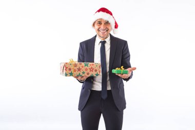 Takım elbiseli, kravatlı, Noel Baba şapkalı, gülümseyen, elinde beyaz arka planda iki hediye tutan bir iş adamı. Noel kutlaması kavramı.
