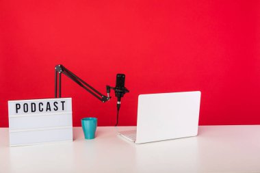 Podcast radyo kayıt stüdyosu, kırmızı arka planda bilgisayar, mikrofon ve podcast 'li ışık kutusu. Podcast, yayın konsepti