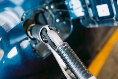 LPG (sıvılaştırılmış petrol gazı) benzinliğinden yapılmış bir arabaya bağlanan hortumun ayrıntıları metalik mavi bir arabada bir benzin istasyonunda. Yakıt ikmali, benzin istasyonu, ekoloji, ulaşım ve eko kavramı.