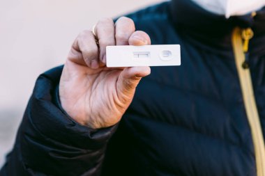 Sokakta elinde negatif antijen testi olan yaşlı bir kadının elinin ayrıntıları. Kavram covid-19, ihu, delta, omicron, saptama testi ve pandemik.