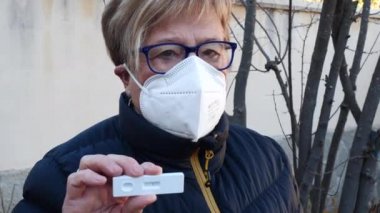 Sokaktaki yaşlı kadın, maske takıyor, antijen testi yaptırıyor. Kavram covid-19, ihu, delta, omicron, saptama testi ve pandemik.