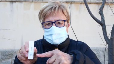 Sokaktaki yaşlı kadın, maske takıyor, antijen testi yaptırıyor. Kavram covid-19, ihu, delta, omicron, saptama testi ve pandemik.