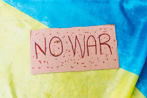 Cardboard sign that reads: 'No War', against the background of the colors of the Ukrainian flag. Concept of war of Ukraine, Russia, inplane, no to war and stop war.