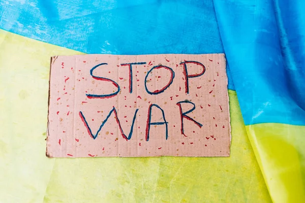 Cardboard sign that reads: \'Stop War\', against the background of the colors of the Ukrainian flag. Concept of war of Ukraine, Russia, inplane, no to war and stop war.