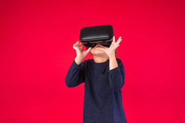 Sanal gerçeklik gözlüğü takan küçük bir kızın kırmızı arka plandaki görüntüsü hayret verici ve dokunaklı. Sanal, geliştirilmiş gerçeklik, teknoloji, oyunlar ve çocukluk kavramı.