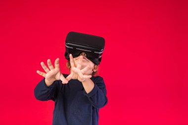Sanal gerçeklik gözlüğü takan küçük bir kızın kırmızı arka plandaki görüntüsü hayret verici ve dokunaklı. Sanal, geliştirilmiş gerçeklik, teknoloji, oyunlar ve çocukluk kavramı.
