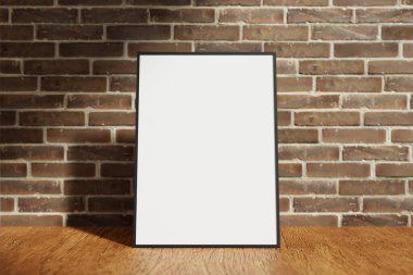Dikey siyah poster ya da ahşap masa üzerindeki bulanık tuğladan arkaplanlı fotoğraf çerçevesi modeli