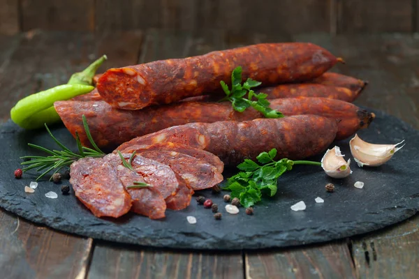 新鮮なハーブやスパイスと黒ボード上の豚肉の肉で作られた乾燥ソーセージ 自家製のスモークソーセージ — ストック写真