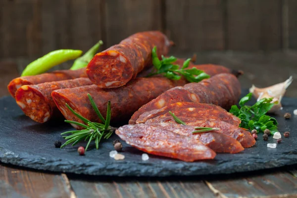 新鮮なハーブやスパイスと素朴な 木製のテーブルの上に豚肉の肉で作られたドライソーセージ 自家製のスモークソーセージ — ストック写真