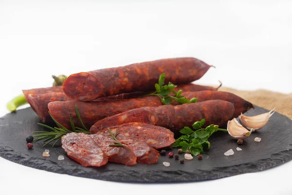 新鮮なハーブやスパイスと黒ボード上の豚肉の肉で作られた乾燥ソーセージ 白地に自家製ソーセージの燻製 — ストック写真