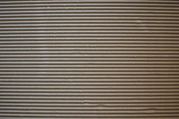 Dark brown corrugated cardboard box textured background with horizontal ridges