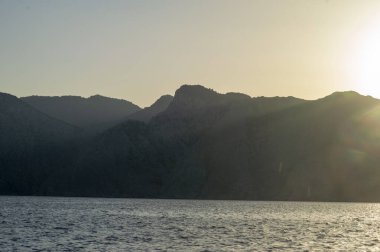 Ege Denizi 'ndeki Yunan adaları üzerinde batmış bir deniz manzarası. Tepelerin silueti