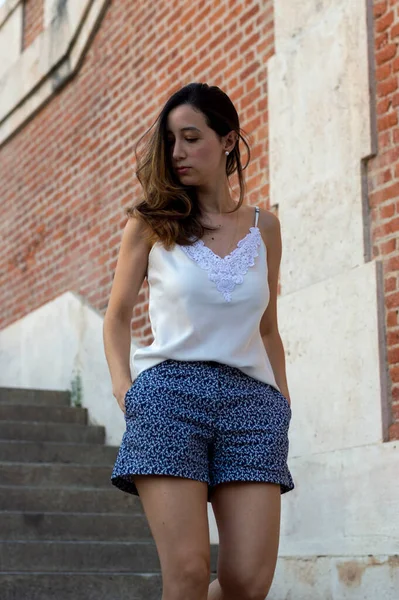 Young woman walking through the Jardines of Sabatini in Madrid. Woman walking using blue shorts and white blouse
