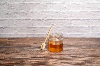 Bal çömleği ve tahta sopa izole edilmiş beyaz tuğla duvar