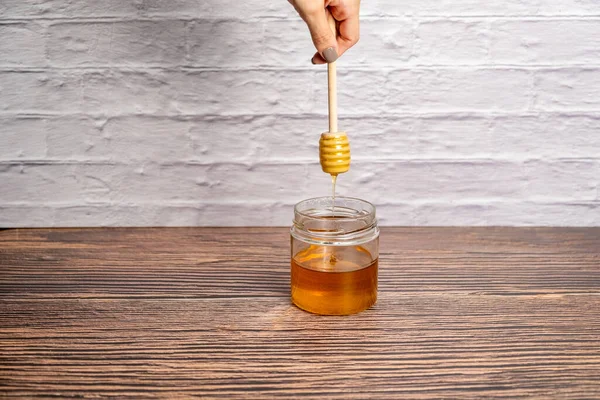 Honey Drizzling Pot Honey Wooden Stick Isolated White Brick Wall — Stock Photo, Image