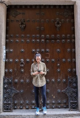 Şehrin ön kapısındaki genç bayan cep telefonuna bakıyor.