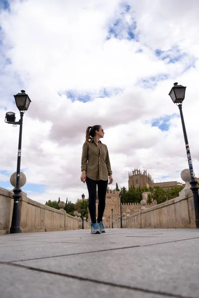 Young woman traveller walking through a bridge using a military green shirt